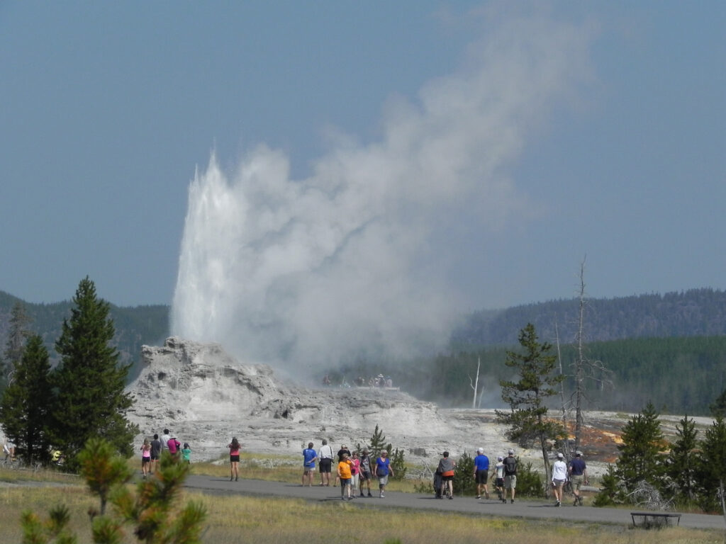 Old Faithful geyser erupting with visitors watching in Yellowstone