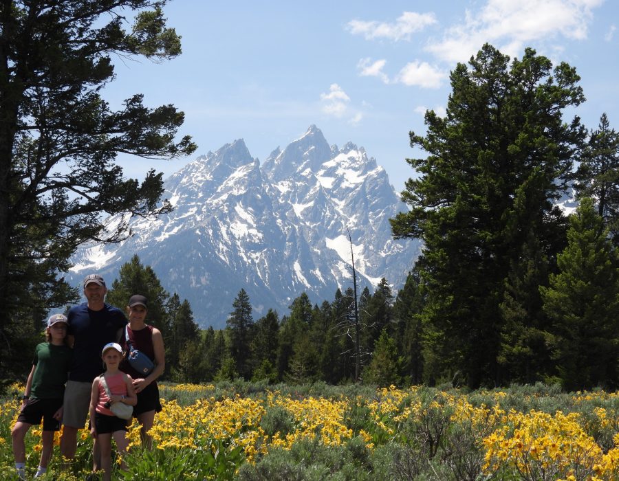 hikers exploring wildflower field with Grand Teton peaks