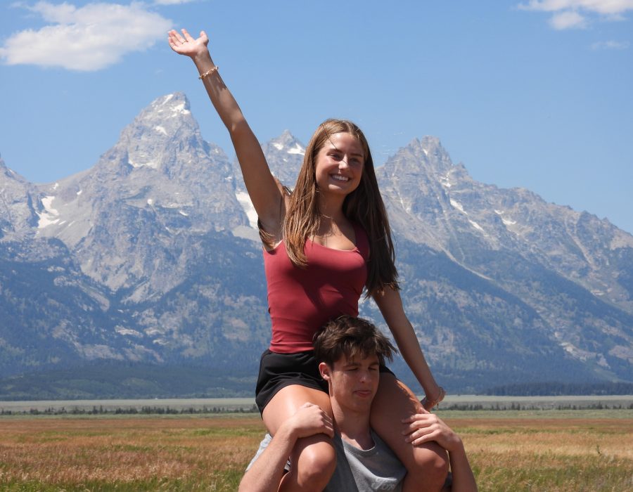 woman celebrating with arms raised in front of Grand Teton peaks